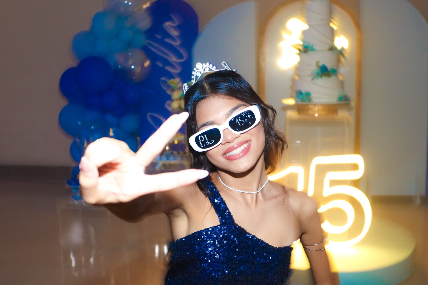 Debutante de óculos escuros em frente ao número 15 iluminado
